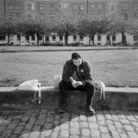 A man reading a book on a park in a European city, black and white